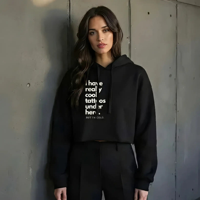 Sassy Model wearing a black hoodie standing in front of a concrete wall